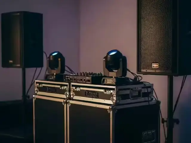 Bocinas profesionales y cabezas móviles junto a una consola de DJ