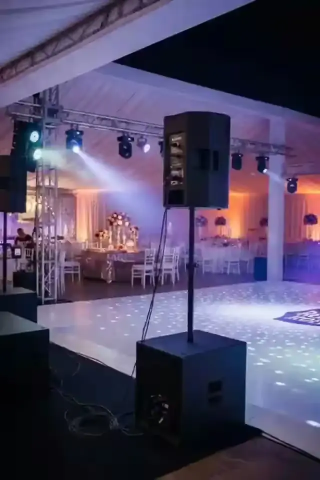 Bocina sobre tripié y estructura de iluminación en un salón de XV años con pista iluminada