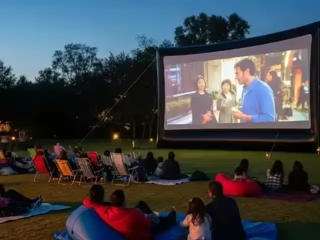 Pantalla inflable gigante con proyección en un parque al anochecer