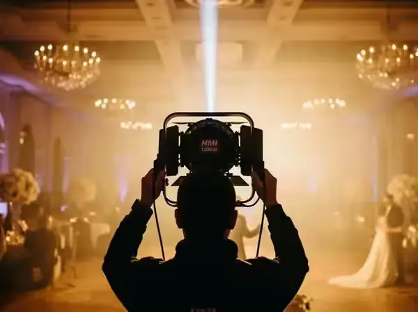 Operador de seguidor de luz enfocando a los novios durante el vals en un salón con candiles