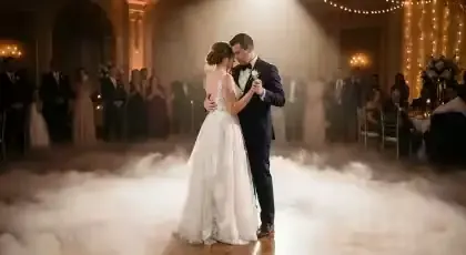 Novios bailando sobre humo bajo en un salón con guirnaldas e invitados alrededor
