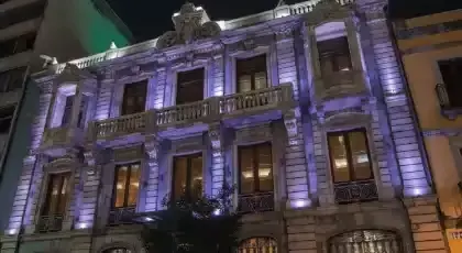 Fachada de un edificio clásico iluminada con luces arquitectónicas en tono violeta